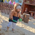 Toddler boy in winter clothes playing on sand