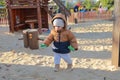 Toddler boy in winter clothes playing on sand