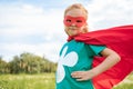 portrait of little child in red superhero costume standing akimbo