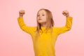 Portrait of little courageous girl standing with raised fists, showing power in small hands and looking with arrogance