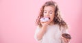 Portrait of a little curly girl eating donuts Royalty Free Stock Photo