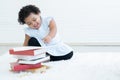 Portrait of Little cute African chubby kid girl use left hand writing on paper on stack of textbooks with toys and sitting