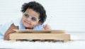 Portrait of Little cute African chubby kid girl wear glasses smiling and use left hand writing on paper at table lying on floor Royalty Free Stock Photo
