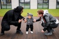 Portrait of little cute baby boy making first steps, holding hands of father and mother, looking at the camera Royalty Free Stock Photo