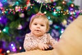 Portrait of little cute baby girl learning walking and standing. with Chrismas tree and lights on background. Adorable Royalty Free Stock Photo