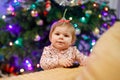 Portrait of little cute baby girl learning walking and standing. with Chrismas tree and lights on background. Adorable Royalty Free Stock Photo