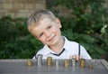 Portrait of a little cute boy in front of whom on the table are lined with columns of coins