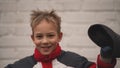 Portrait of little cute boy in jacket with red collar with baby cap in hand