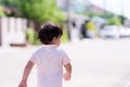 Portrait of little cute boy running on the road in front of house. Royalty Free Stock Photo