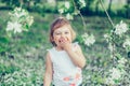 Portrait of little cute disheveled girl laughing and having fun outdoors among flowering trees in a sunny summer day