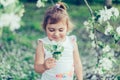 Portrait of little cute disheveled girl laughing and having fun outdoors among flowering trees in a sunny summer day