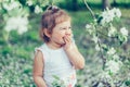 Portrait of little cute disheveled girl laughing and having fun outdoors among flowering trees in a sunny summer day