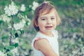 Portrait of little cute disheveled girl laughing and having fun outdoors among flowering trees in a sunny summer day