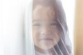 Portrait little cute girl. Attractive beautiful little child hiding behind curtain at house. Nursery child looks so lovely and Royalty Free Stock Photo