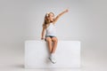 Portrait of little cute girl in casual clothes sitting on big box isolated on white studio background. Happy childhood Royalty Free Stock Photo