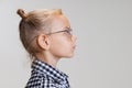 Close-up side view portrait of little cute girl, child in stylish glasses isolated over gray background Royalty Free Stock Photo