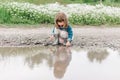 Portrait of little cute girl on the field with daisies and water