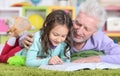 Portrait of little cute girl with grandfather reading book Royalty Free Stock Photo