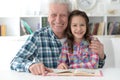 Portrait of little cute girl with grandfather reading book Royalty Free Stock Photo