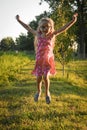 Portrait of little cute girl jumps for joy and smiling. Outdoors on a background of green grass and forest Royalty Free Stock Photo