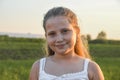 Portrait of little cute girl looking into the frame smiling. Outdoors on a background of green grass and forest Royalty Free Stock Photo