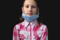 Portrait of a little cute girl with a medical mask isolated on black background Royalty Free Stock Photo