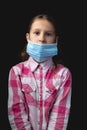 Portrait of a little cute girl with a medical mask isolated on black background Royalty Free Stock Photo