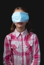 Portrait of a little cute girl with a medical mask isolated on black background Royalty Free Stock Photo