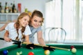 Portrait of little cute girl with mother playing billiards