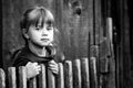 Portrait of little cute girl near vintage rural fence. Black and white photography.