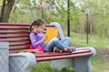 Portrait of little cute girl with open book is sitting on the wooden bench Royalty Free Stock Photo