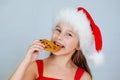 portrait little cute girl in santa hat eating christmas cookies Royalty Free Stock Photo