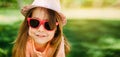 Portrait of a little cute girl wearing a hat and sunglasses outdoors. Copy space. Royalty Free Stock Photo