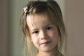 Portrait of little cute pretty young child girl with gray eyes and scattered blond hair smiling shyly in camera on blurred gray ba Royalty Free Stock Photo