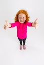 Portrait of little cute redheaded girl, child in pink sweater posing isolated over white studio background.