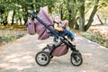 Portrait of little cute toddler girl sitting in stroller or pram and going for a walk. Happy cute baby child having fun Royalty Free Stock Photo