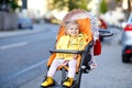 Portrait of little cute toddler girl sitting in stroller or pram and going for a walk. Happy cute baby child having fun Royalty Free Stock Photo