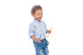 A portrait of a little dark-skinned boy with curly hair in jeans and a light-colored shirt is standing in profile and Royalty Free Stock Photo