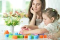 Little daughter and happy mother playing with colorful plastic blocks Royalty Free Stock Photo