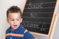 Portrait of little elementary school pupil with text of Back To School on the blackboard.