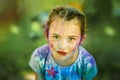 Portrait of little emotional 6 years old girl with face smeared with holi colors in sunny summer day. Concept for Indian festival Royalty Free Stock Photo