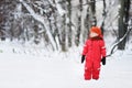 Portrait of little funny boy in red winter clothes having fun with snow during snowfall Royalty Free Stock Photo