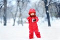 Portrait of little funny boy in red winter clothes having fun with snow during snowfall Royalty Free Stock Photo