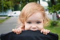 Portrait of a little funny child girl blond with blue eyes sitting in a baby stroller in the summer for greens. A funny Royalty Free Stock Photo