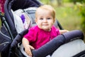 Portrait of a little funny child girl blond with blue eyes sitting in a baby stroller in the summer for greens. Trinasport for a c Royalty Free Stock Photo