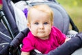 Portrait of a little funny child girl blond with blue eyes sitting in a baby stroller in the summer for greens. Trinasport for a c Royalty Free Stock Photo