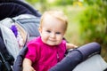 Portrait of a little funny child girl blond with blue eyes sitting in a baby stroller in the summer for greens. Trinasport for a c Royalty Free Stock Photo