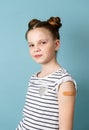 Portrait little girl with adhesive plaster on shoulder posing isolated. Covid-19 prevention