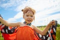 Portrait of little girl with Asian eyes and butterfly wings having fun and joy in meadow or field with grass and flowers Royalty Free Stock Photo