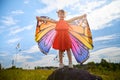 Portrait of little girl with Asian eyes and butterfly wings having fun and joy in meadow or field with grass and flowers Royalty Free Stock Photo